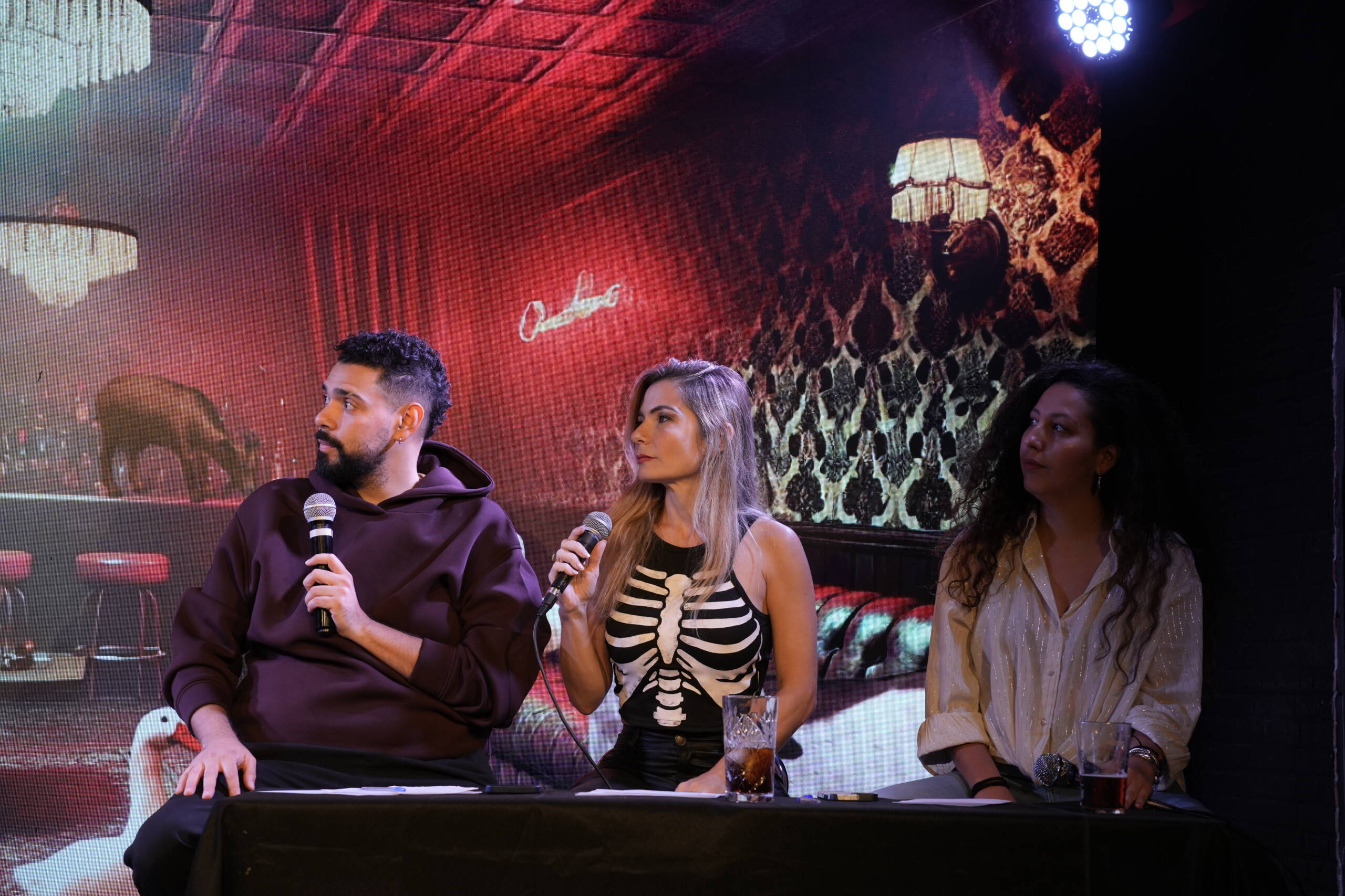 Three guests seated at a table on stage with microphones