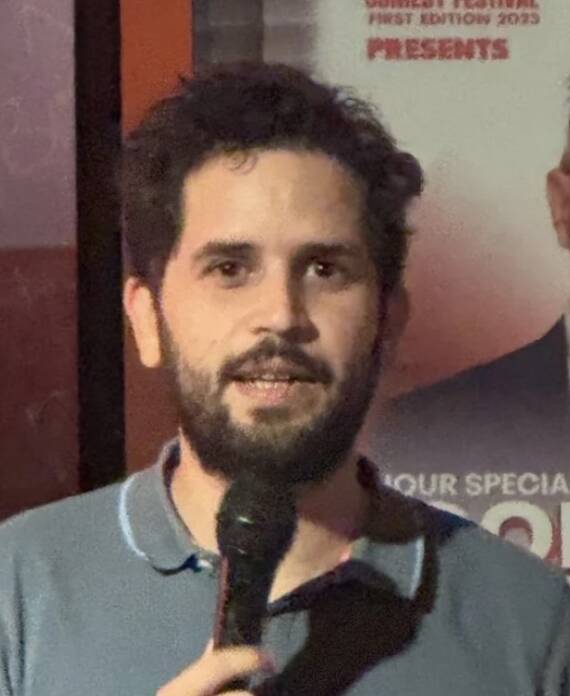 Comedian performing under red stage lights at a Madrid Comedy Festival show