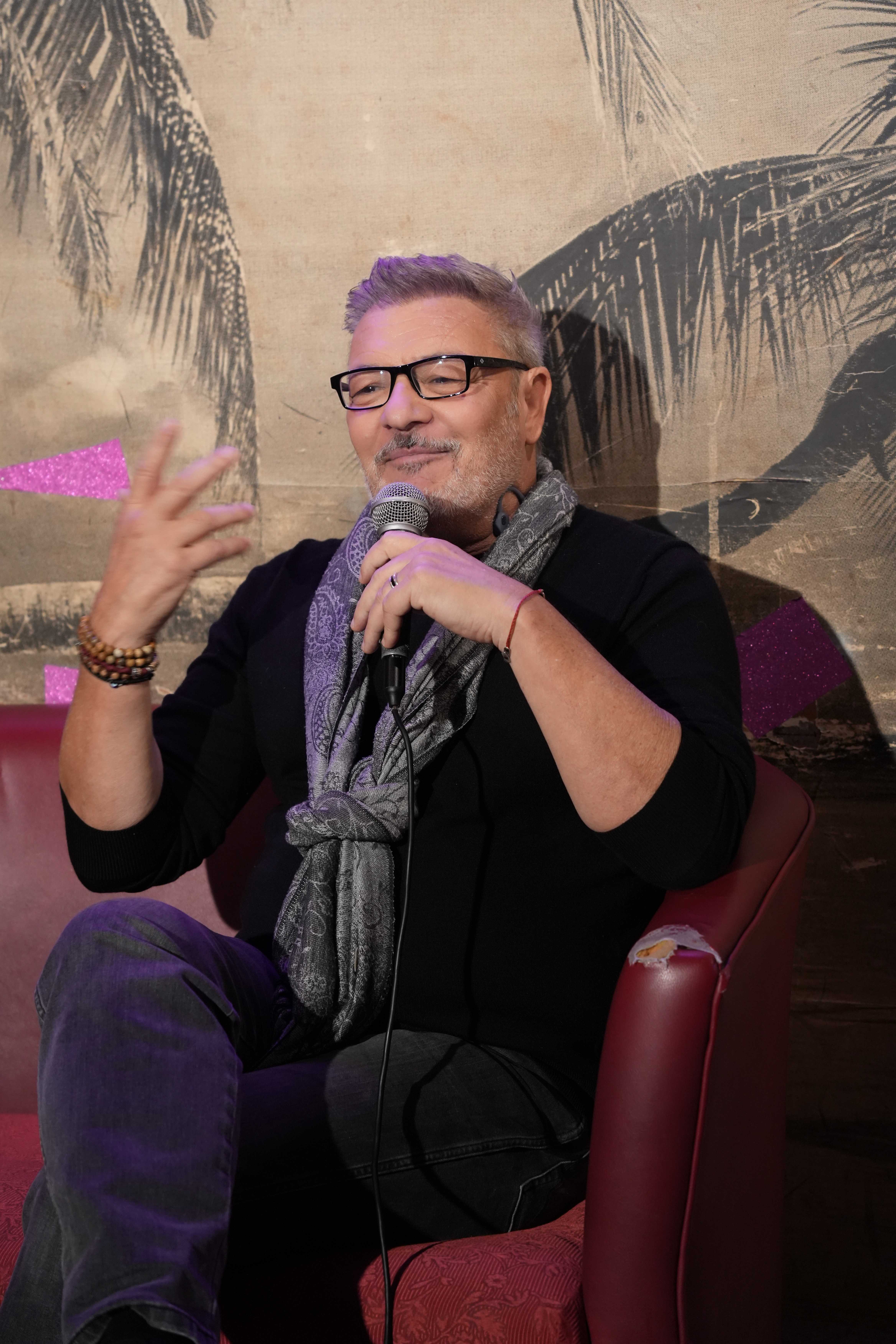 Dzimis Tapas seated during an interview, speaking into a microphone