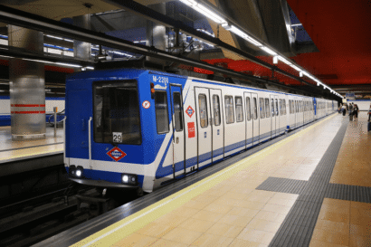 A blue Madrid Metro train arriving at a station platform