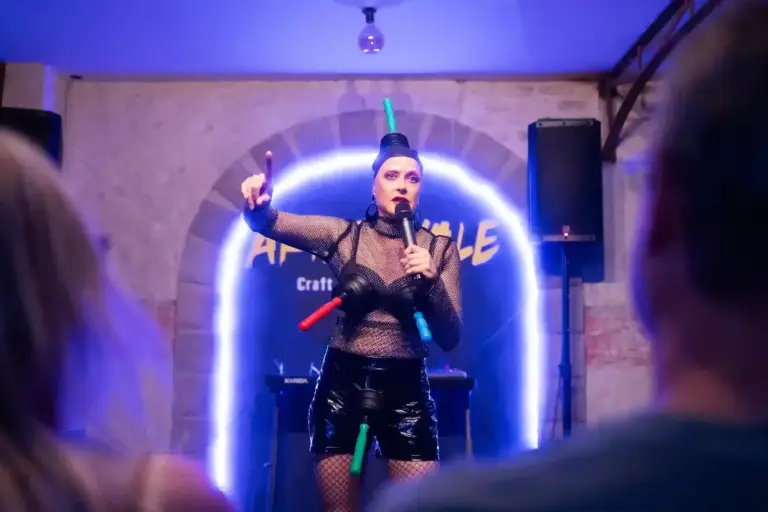 Performer in fishnets and a tall headpiece on stage at Artizanale