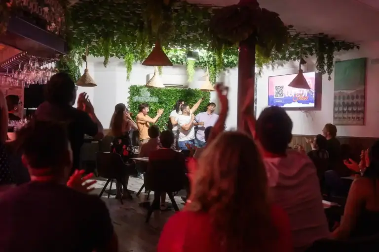 Crowd cheering with raised arms under red lights at Tropicana