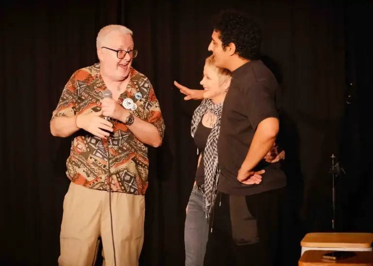 Three performers sharing a laugh on stage