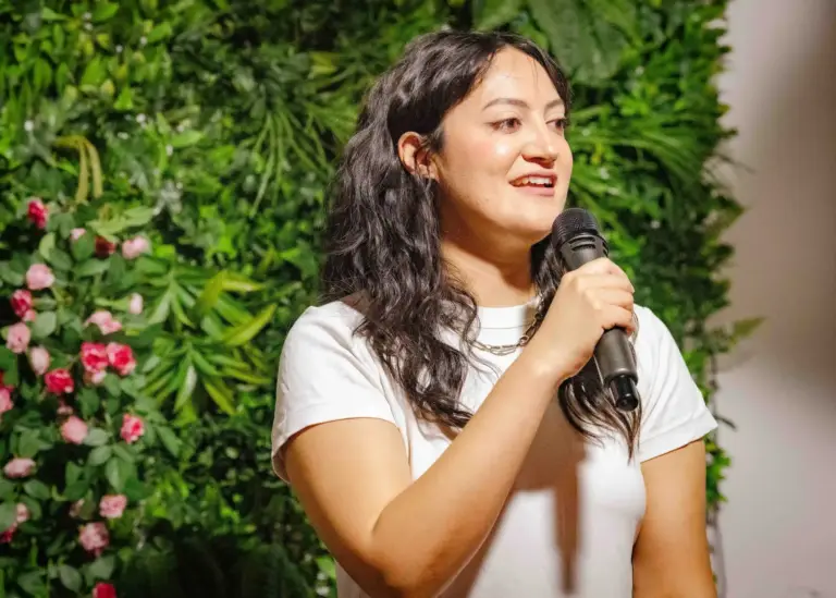 Comedian in a white T-shirt speaking into the microphone at Tropicana